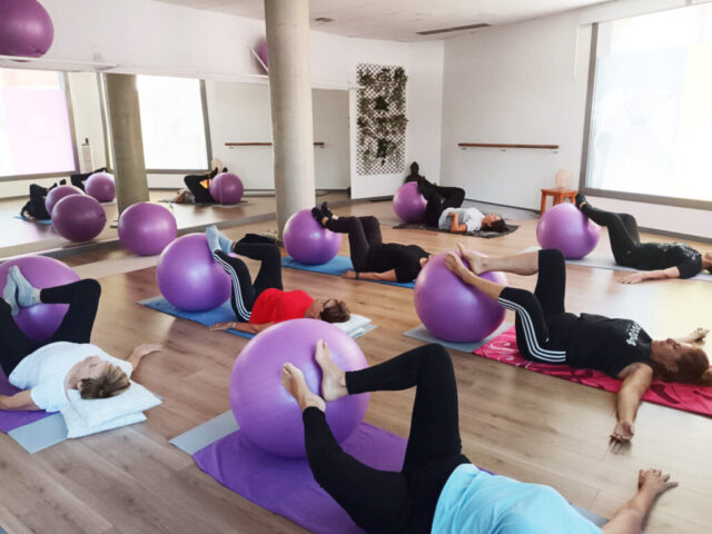 Grup de persones estirades amb les cames recolzades sobre pilotes d’estabilitat.