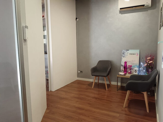 Sala d’espera amb dues butaques grises i taula amb decoració.